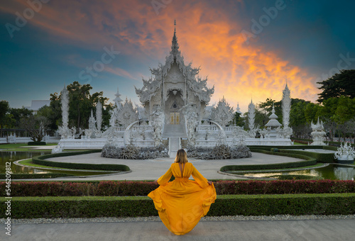 Wat Rong Khun or White Temple at sunset. Tourist girl looking towards the temple. Thailand's top travel destinations. Chiang Rai, Thailand