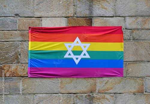 Gay pride rainbow flag with Star of David, pinned to a stone wall