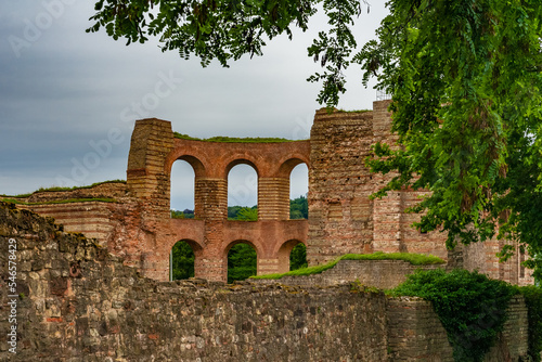 Picturesque view over the wall to the central apse of the famous Trier Imperial Baths (Kaiserthermen), a large Roman bath complex in Trier, Germany, on a cloudy day.
