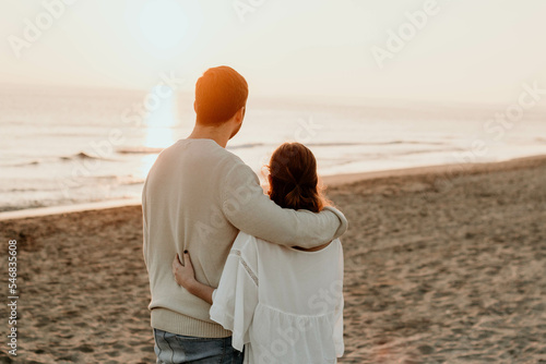 Pareja de enamorados disfrutando del atardecer desde la orilla