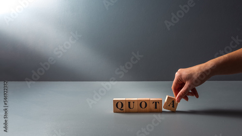 womans hand posing wooden block with the word quota . cocept of work Quota's .equality.