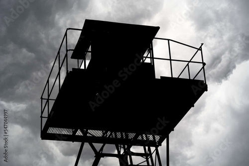 Dark silhouette of the metal structure of the watchtower, clouds in the background