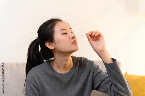 Young Asian girl taking herself a nasal swab for a rapid self test