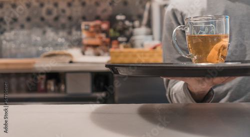 Detalle de camarero irreconocible, llevando la bandeja con el té, en la barra del restaurante.