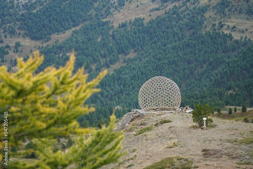 View of a sphere on the hill with green forest in the background. Claviere, Italy.