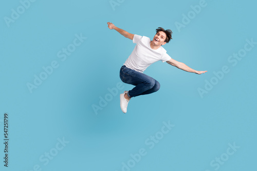 Full size photo of young happy excited smiling positive man jumping isolated on blue color background