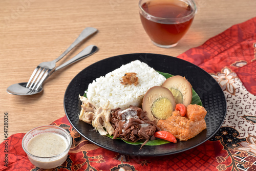 Gudeg is a traditional dish from Yogyakarta, Indonesia. Made from young unripe jack fruit. Served with rice, krecek, telur bacem, and shreded chicken. Served on plate with tea