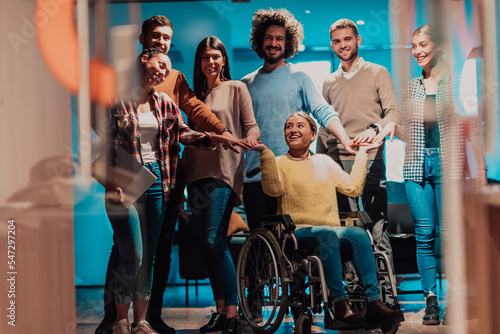 Businesswoman in a wheelchair on break in a modern office with her team in the background