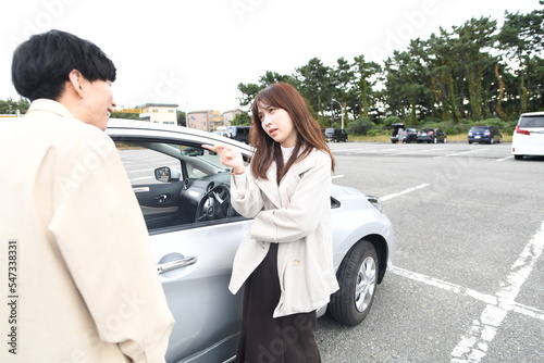 車の前で喧嘩する男女の若いカップル