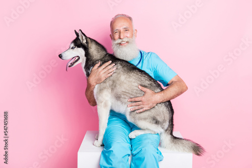 Photo of professional vet man hold big fluffy alaskan malamute examine shelter doggy isolated on pastel color background