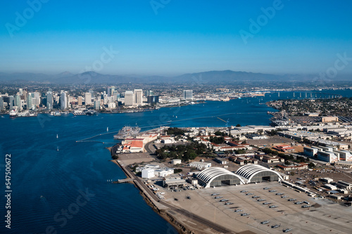 Aerial view of North Island Naval Air Base on Coronado and downtown San Diego California while flying over the bay with boats on the water and mountains in the background during daylight