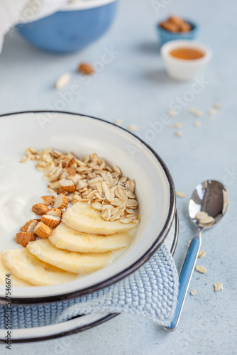 Domowe, zdrowe śniadanie. Jogurt naturalny z płatkami owsianymi, bananem i migdałami.