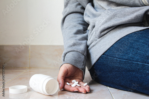 Hand with pills on floor.Woman suicide by taking overdose medicines.Young woman is major depressive disorder.