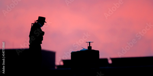Silhouette eines Kaminkehreres vor rotem Abendhimmel