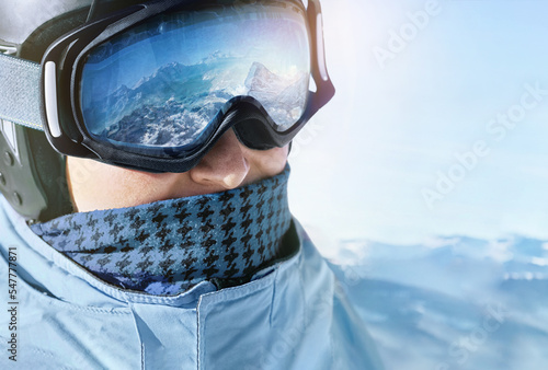 Close up of the ski goggles of a man with the reflection of snowed mountains.