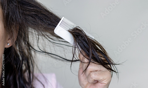 woman applying serum oil on wet hair with pipette or using white comb to disentangle isolated.healthy strong hair,growth stimulation stop fall shiny.top of head forehead lateral view.after pregnancy