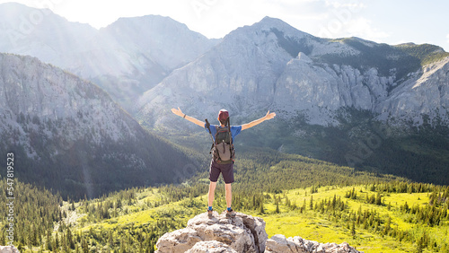 Hiker person standing on a rock above deep valley with mountains in the background, Banff National Park, Alberta, Canada.