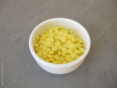 A bowl of light yellow cocoa butter chips as an ingredient for cooking and baking, chocolate making or personal care products