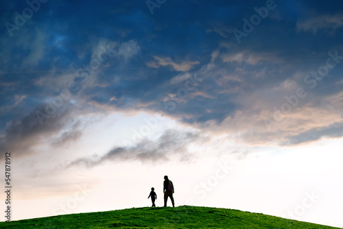 Silhouette of a person following child against minimalist landscape