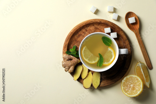 Delicious ginger tea and ingredients on beige background, flat lay. Space for text