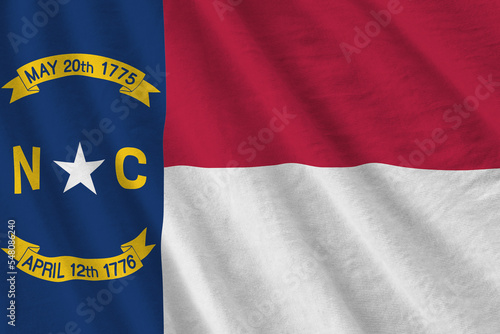 North Carolina US state flag with big folds waving close up under the studio light indoors. The official symbols and colors in banner