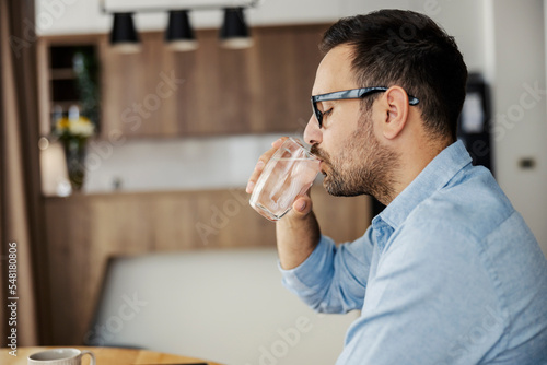 Profile of thirsty man drinking fresh water at home.