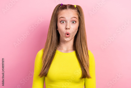 Photo of positive optimistic schoolgirl with ponytails dressed yellow long sleeve impressed staring isolated on yellow color background