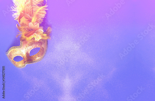 Golden Carnival mask on neon background with sparkles. Mardi Gras concept or New Years decoration. Concept festive background or design. Close-up