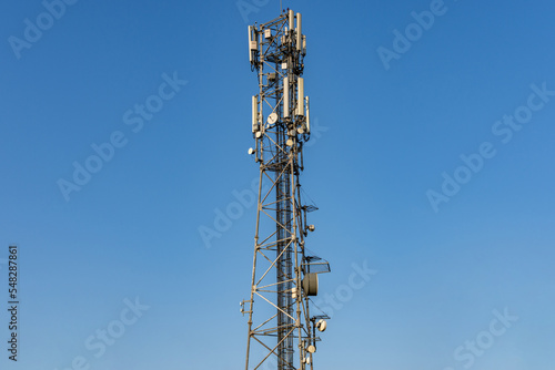 5G antenna communication tower with dish against a clear blue sky