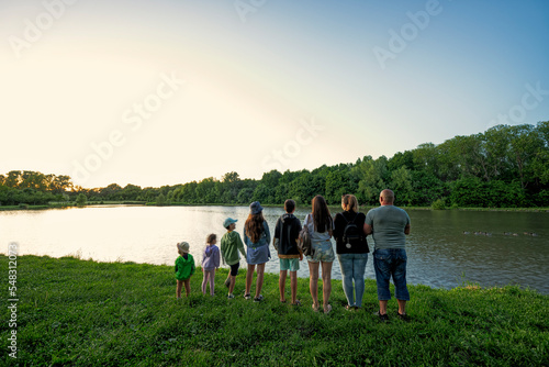 Big and large family against lake in sunrise. Six children. Parents and kids.