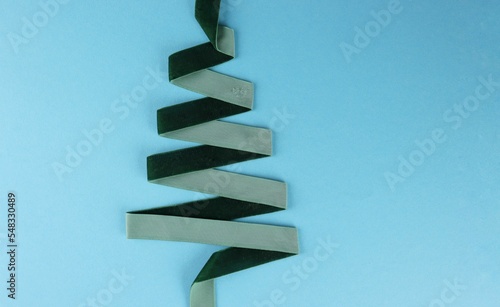 Christmas tree made of green ribbon on a blue background view from above