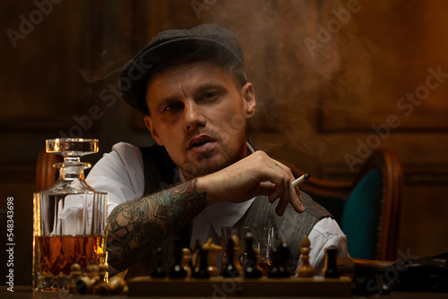 Young gangster smoking and drinking alcohol while playing chess