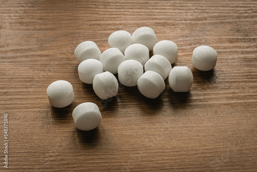 Naphthalene mothballs on wooden background.