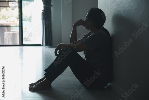 Schizophrenia with lonely and sad in mental health depression concept. Depressed woman sitting against wall at home with a shadow on wall feeling miserable. Women are depressed, fearful and unhappy.