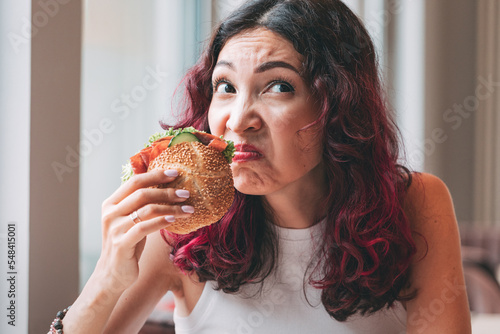 A girl sniffs a spoiled burger. Fast food diet and food poisoning concept