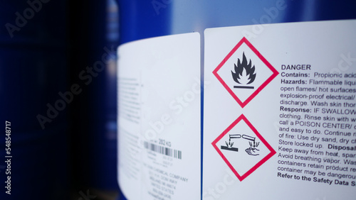 Flammable, acid, volatile, warning labels, mounted on hazardous chemical storage tanks in the warehouse of a chemical industrial factory plant. Waiting for delivery according to the user's order.