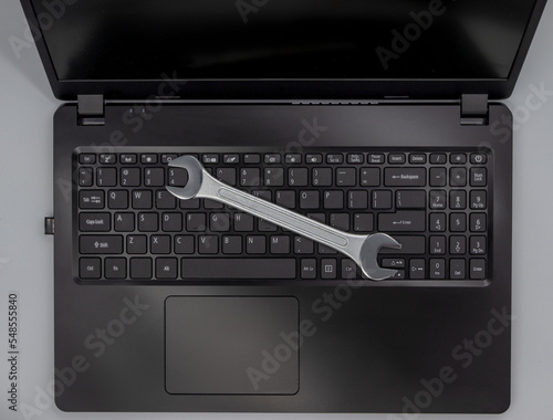 Stalowy klucz leżący na klawiaturze laptopa, naprawa komputera.