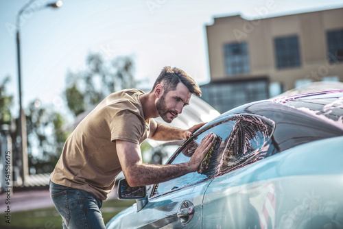 Auto detailer cleaning the exterior of a client motor vehicle