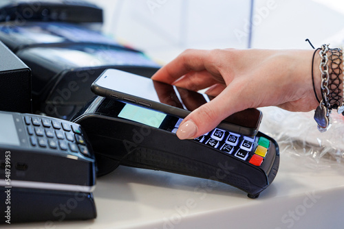 Dettaglio del pagamento con carta di credito con uno smartphone verso il pos di tenuto dalla mano di una commessa 