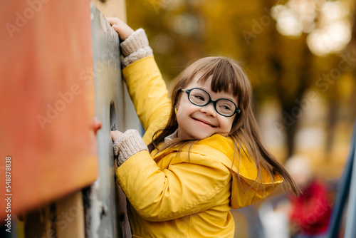 Happy child with down syndrome enjoying swing on playground