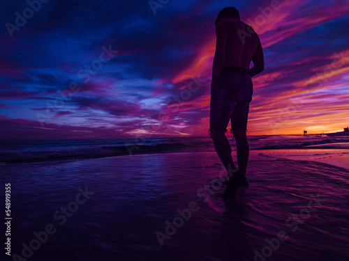 man standing on the pensacola beach during sunset with vibrant colors