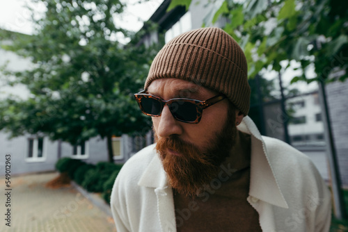 suspicious man with beard in stylish sunglasses and beanie hat.