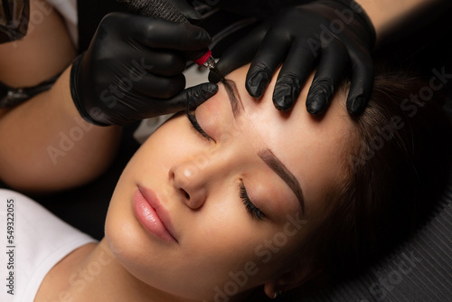 Cosmetician making permanent makeup with a machine