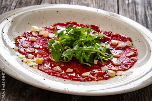 Beef carpaccio with parmesan and arugula on wooden table 