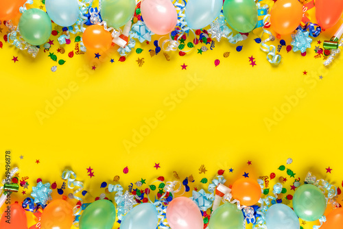 Birthday background top view. Frame of balloons and various party decorations on a yellow background