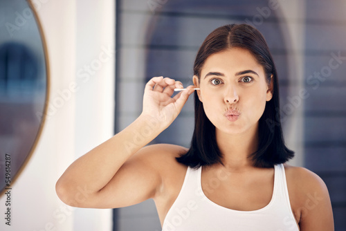 Woman, mirror and cleaning ear in morning in home, bathroom and self care for personal hygiene. Girl, health and beauty in house for clean, self love and cleanliness with q-tip for wax in Los Angeles