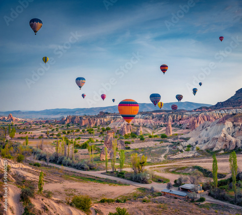 Flying on balloons early morning in Cappadocia. Spectacular summer sunrise in Red Rose valley, Goreme village location, Turkey, Asia. Traveling concept background..