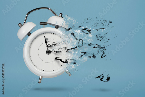 Time is running out. White alarm clock with flying numbers as a symbol of lost time. The concept of time is running out, loss or lack of time, an alarm clock with numbers shatters into small pieces.