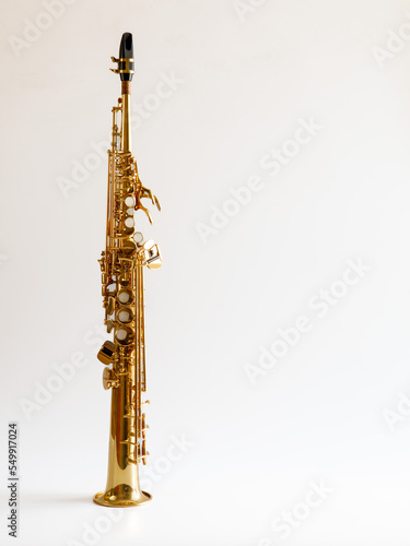 Soprano Sax, wind instrument saxophone staying on a white background, vertical, copy space.