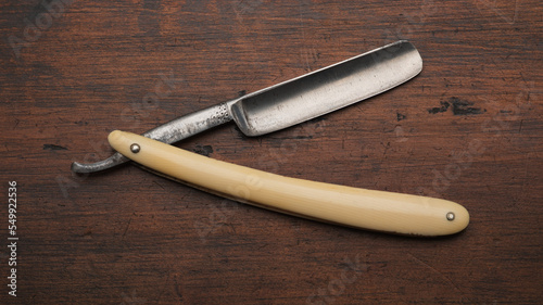 An old straight or cut throat razor overhead view lying on an aged wooden surface